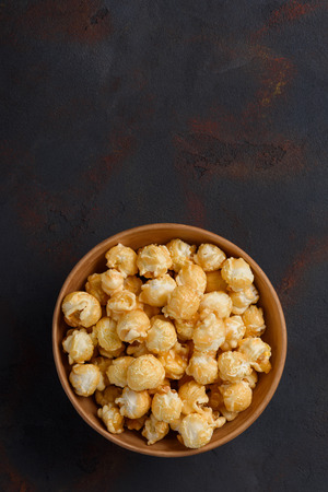 Caramel popcorn in bowl vertical on dark table with copy spaceの写真素材