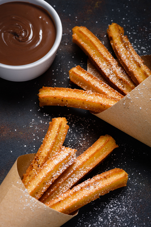 Churros with sugar cinnamon and chocolate sauce dip on dark backgroundの写真素材