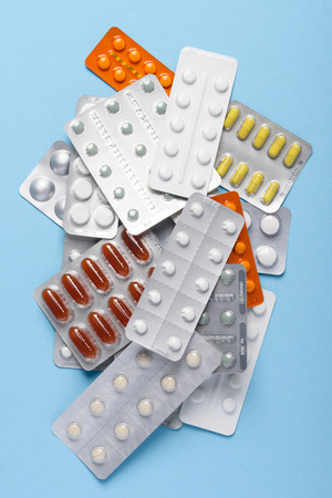 Pills drugs in blisters assortment heap on blue pastel background top viewの写真素材
