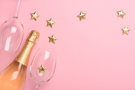 Champagne with glasses and golden stars on pink backgroundの写真素材
