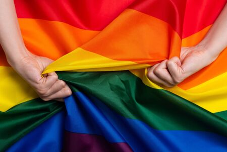 Woman hands pull rainbow Pride flag concept top viewの写真素材
