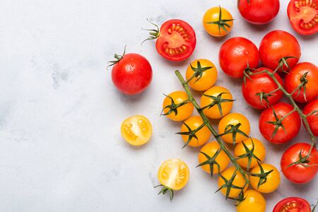 Small cherry tomatoes assortment, fresh red ripe on branch, red and yellow, whole and cut in half, on rustic table flat lay with copy space.の写真素材