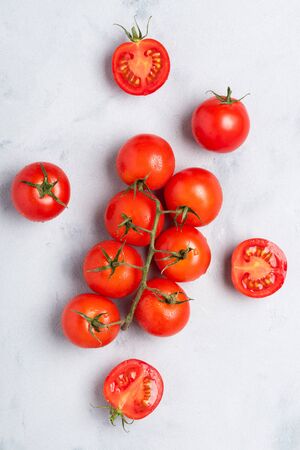 Tomatoes, fresh red ripe on branch, whole and cut in half, on rustic table top view.の写真素材