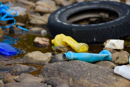 Enviroment pollution. Old tire bottles and plastic trash on ocean shore.の写真素材