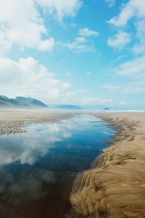 Puddle with reflection on the beach during ebbの写真素材