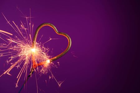 Brightly burning sparkler heart shaped. Love wedding valentines day party bengal fire.の写真素材