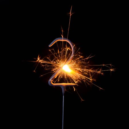 Burning sparkler in shape of number two, digit 2, isolated on black background.の写真素材