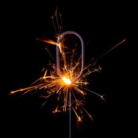 Burning sparkler in shape of number zero, digit 0, isolated on black background.の写真素材