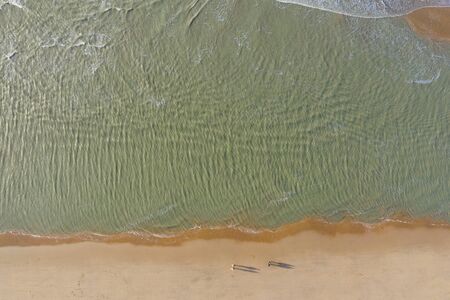 People walking on a north sea sandy beach, aerial drone viewの写真素材