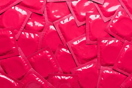 Condoms background top view. Red foil packaging latex rubber condom backdrop.の写真素材