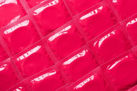 Condoms in pink foil packaging background top viewの写真素材