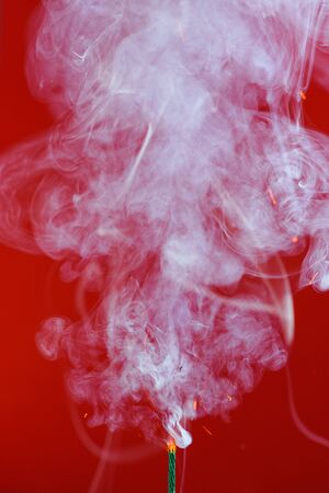 Pyrotechnics wick fuse burning with smoke and sparks on red backgroundの写真素材