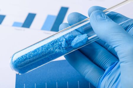 Scientist hold glass test tube with blue crystals in labの写真素材