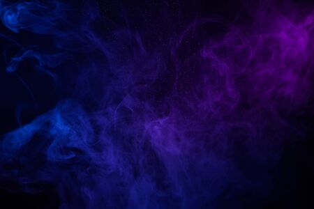 Colorful clouds of smoke and shiny dust on dark backgroundの写真素材