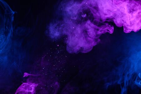 Shiny glitter falling in clouds of pink and blue smoke abstract backgroundの写真素材