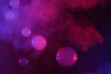 Soap bubbles filled with smoke flowing over abstract colorful clouds of vaporの写真素材