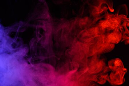 Colored smoke clouds flowing dark abstract backgroundの写真素材