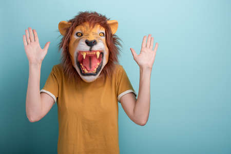Young woman in lion mask holding hands up in desense or stop gesture.の写真素材