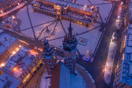 Krakow Poland main square Rynek of the Old Town in winter aerial view. St. Mary's Basilica Gothic church and Krakow Cloth Hall, covered in snow at evening with Christmas tree and decorations.の写真素材