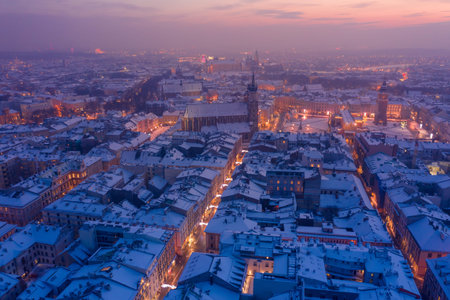 Main square Rynek of the Old Town of Krakow Poland in winter aerial view. St. Mary's Basilica Gothic church, Town Hall Tower, Krakow Cloth Hall, Wawel Royal Castle on background covered in snow at twilight with New Year decorations and lights.の写真素材