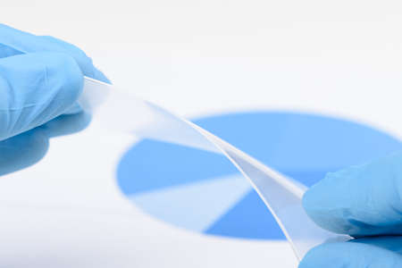 Scientist hold and bend flexible transparent plastic like material in laboratory. Concept of research and discovery of material with new properties.の写真素材