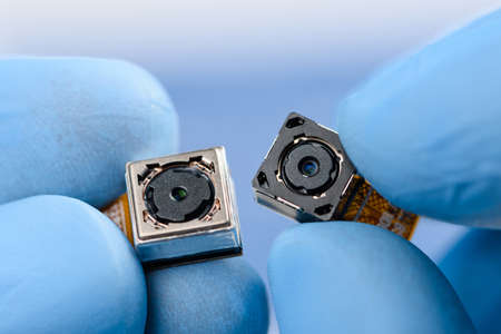 Two camera modules in scientist hands. Different sensor and technology smartphone new high resolution cameras in laboratory.の写真素材