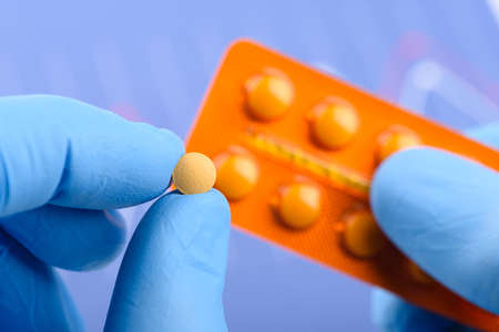 Scientist hold small pill in one hand and blister pack in otherの写真素材