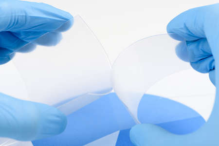 Scientist hold and bend two pieces of flexible transparent plastic like material in laboratory. Concept of research and discovery of new material.の写真素材