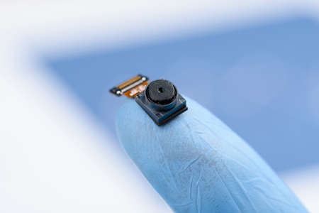 Camera module on fingertip. Smartphone cell phone small camera sensor with high resolution, research or repair concept.の写真素材