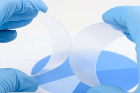 Scientist hold and bend two pieces of flexible transparent plastic like polymer material in laboratory. Research and discovery of new material concept.の写真素材