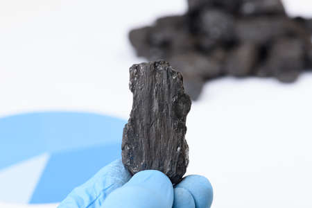 Coal lump in scientist hand. Laboratory coal analysis, fossil fuel research.の写真素材