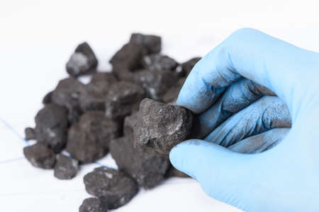 Coal lump in scientist hand. Laboratory coal analysis, fossil fuel research.の写真素材