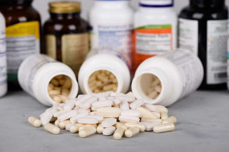 Bottles of vitamins and dietary supplements with pills on tableの写真素材