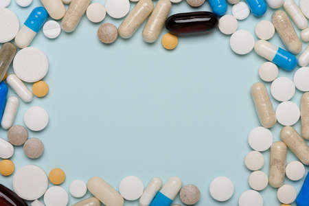 Medicine pills assortment in frame composition on blue background top view with copy spaceの写真素材