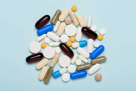 Heap of different medical pills and supplement capsules on blue background top viewの写真素材