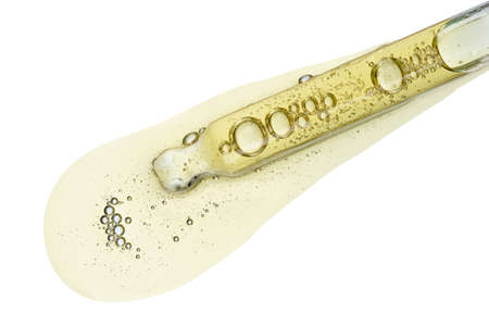 Cosmetic dropper with yellow oil serum in pipette with bubbles isolated on white background top viewの写真素材