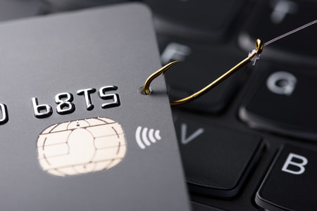 Credit card phishing scam concept. Credit card data theft, card hooked by hacker cyber criminal on fishing hook on keyboard.の写真素材