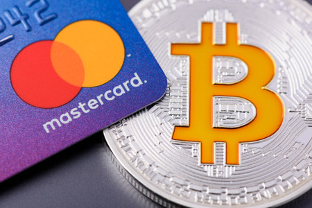 Krakow, Poland - April 29 2022: Mastercard plastic credit payment card with Bitcoin coinのeditorial素材