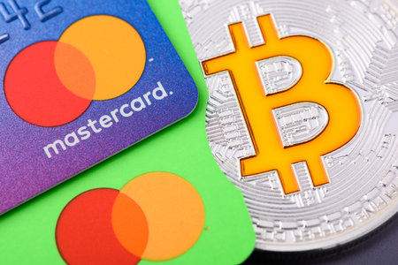 Krakow, Poland - April 29 2022: Mastercard plastic credit payment cards with Bitcoin coinのeditorial素材