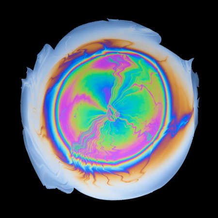 Interference colors from an oil film on water isolated on black background top viewの写真素材