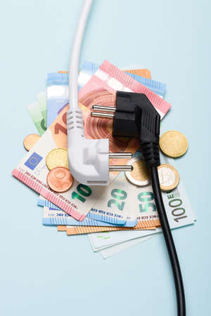 Electric power plugs on Euro banknotes on blue background. Concept of expensive electricity costs and rise in energy bill prices.の写真素材