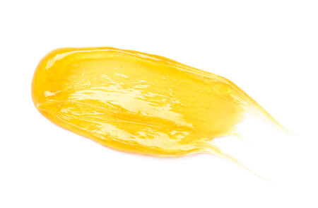 Clear transparent yellow face cream smear smudge, golden sugar honey isolated on white background top view.の写真素材