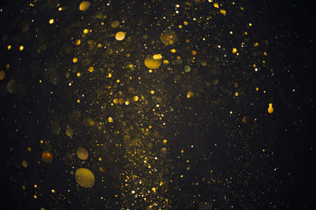 Gold glitter particles lights abstract bokeh dark backgroundの写真素材
