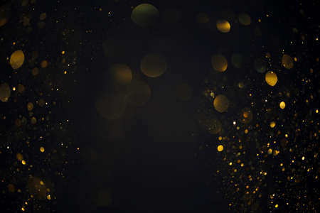 Dreamy golden swirly bokeh glitter lights overlay on dark backgroundの写真素材