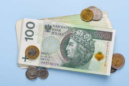 Stack of polish paper currency, 100 zloty PLN bills and coins, on blue background top viewの写真素材