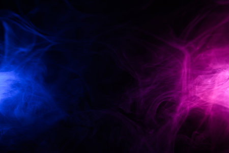 Clouds of colorful blue and purple smoke dark abstract backgroundの写真素材