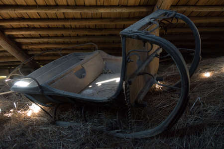 Old Russian sleigh in the attic under the roof in a barn in ancient, hay, falling sunlightの写真素材