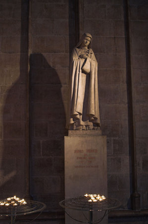 Monument of Saint Theresa with bunch of roses at her feet and burning candles in the foregroundのeditorial素材
