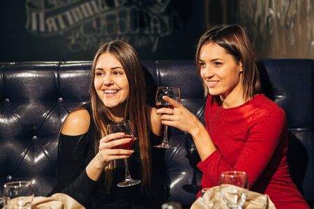 two young beautiful woman relaxing in the restaurant and drinking wine,the two women laughの写真素材