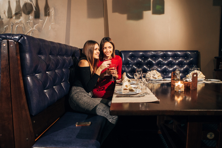 two beautiful young women saw something in the restaurant,two young beautiful woman relaxing in the restaurant and drinking wineの写真素材